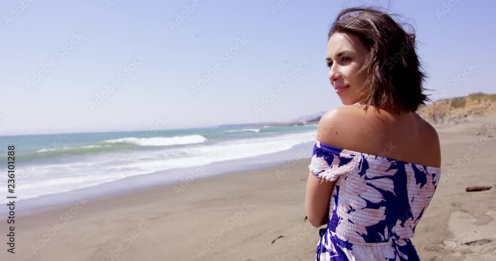 Beautiful young woman on beach looks over shoulder and up towards sky as if something was approaching Beautiful young woman on beach looks over shoulder and up towards sky as if something was approaching