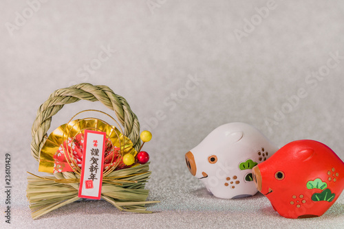 Japanese New Year's Cards with black handwriting ideograms Gingashinnen which means Happy New Year with cute Zodiac animals figurines of two boars on silver background.  © kuremo