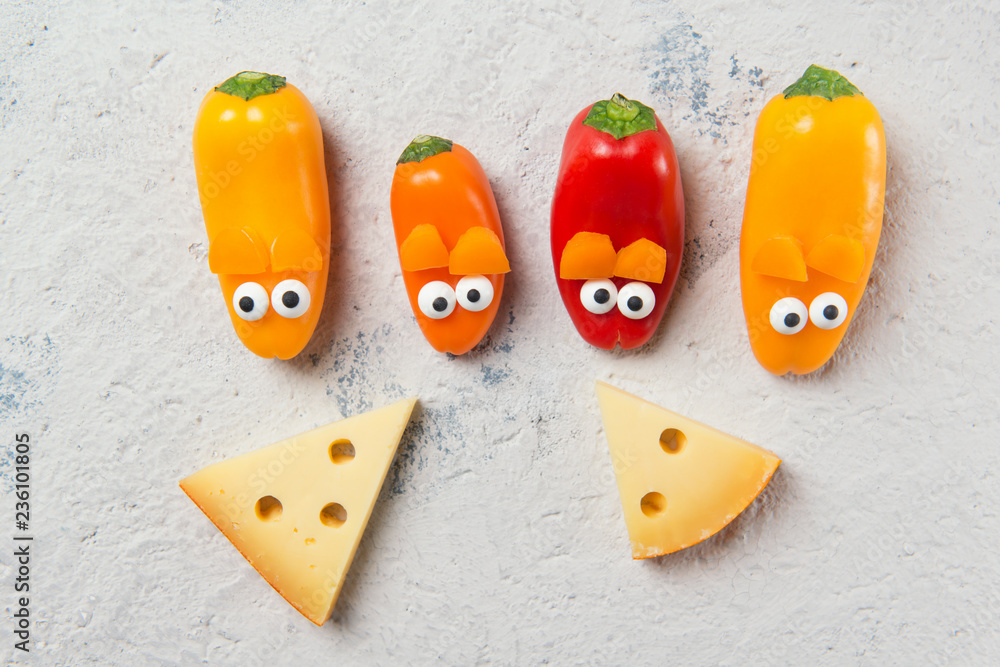 Obraz premium Colorful sweet mini peppers in the shape of mouses and pieces of cheese, stone table, top view, snack for kids idea