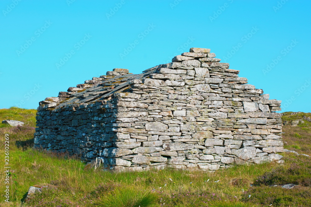 Ancient stone cottage old barn built of granite stones against the blue sky at summer in the polar valley Norway.