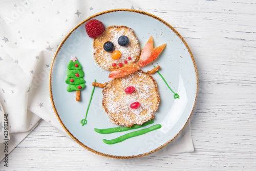 Pancakes in the shape of snowman on ski, Christmas breakfast for kids idea, top view photo