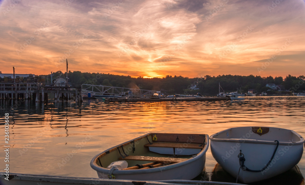 Early morning summer sunrise over calm water and john boats near a working lobster wharf in Muscongus Bay, Maine