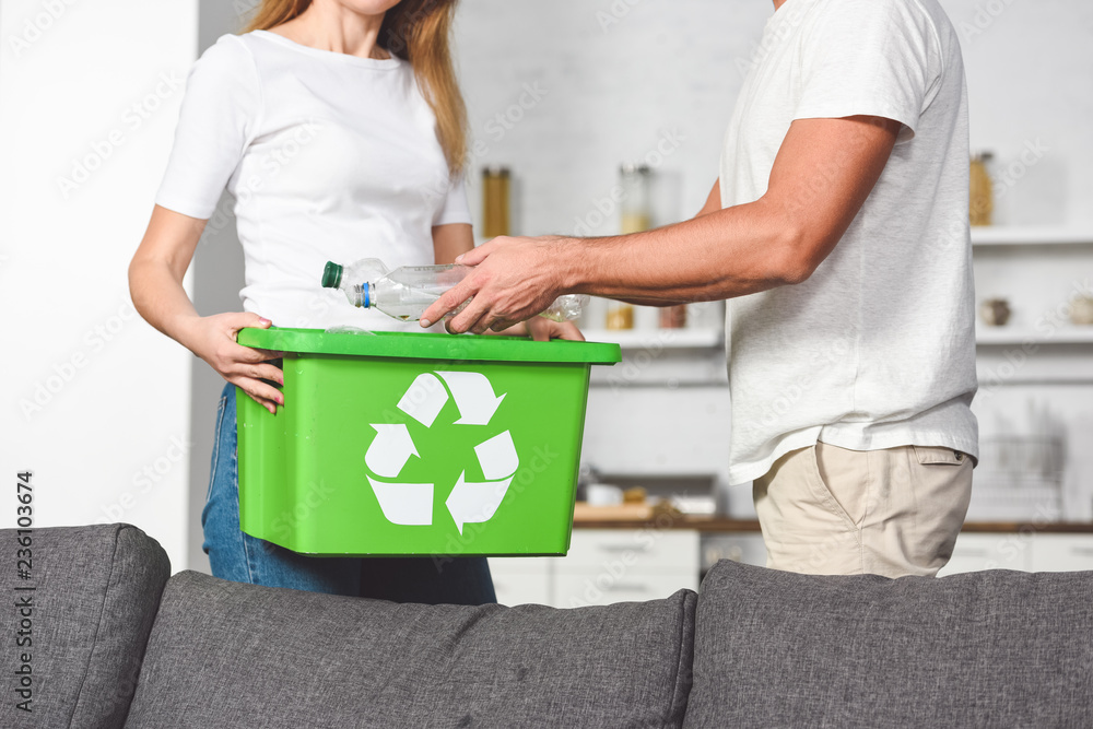 cropped view of adult couple putting empty plastic bottles in recycle green box cropped view of adult couple putting empty plastic bottles in recycle green box