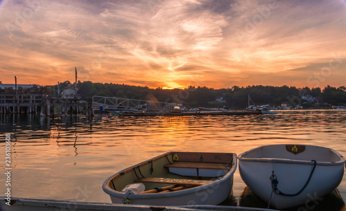Early morning summer sunrise over calm water and john boats near a working lobster wharf in Muscongus Bay, Maine
