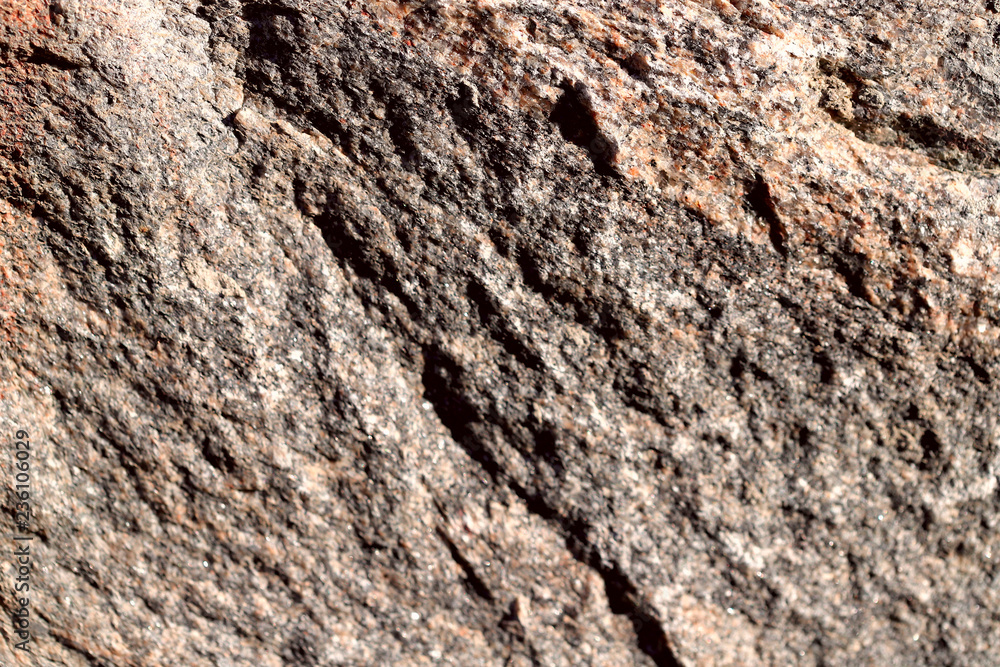 The structure of natural unpolished granite is light brown in color. Natural background, cropped shot, close-up. Conception of nature and production.