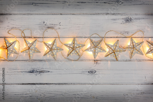 A string of golden star christmas lights, on a destressed woodern background