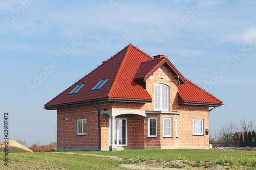 Jaslo, Poland - 7 8 2018: Modern design of a small single-family house located in a rural area. Designing buildings and landscape. New home for people. Red metal roof. Energy saving and greenhouse eff © Xato Lux