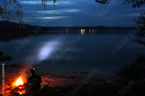 a tourist is sitting by a campfire at night