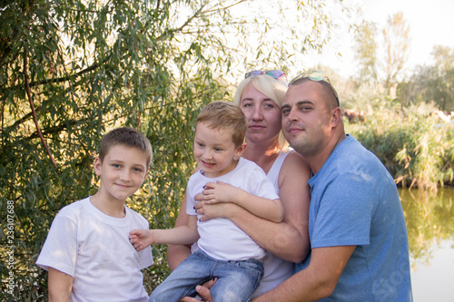 Happy parents of two boys relaxing in nature