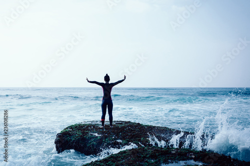 Freedom Woman outstretched arms at seaside mossy reef