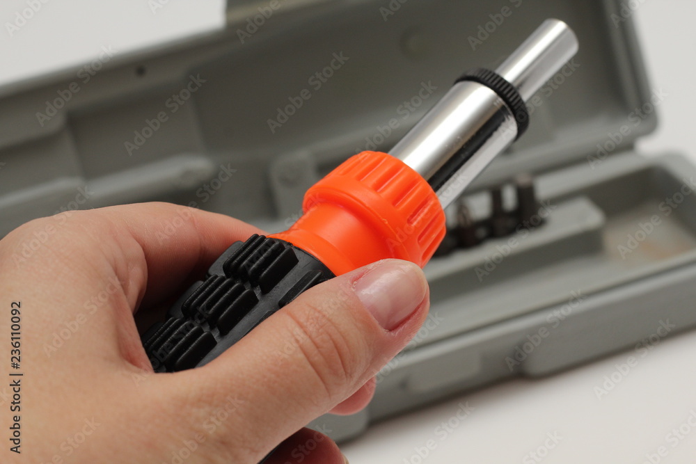 Master holds in his hands a screwdriver. Screwdriver set in box on white background. Master holds in his hands a screwdriver. Screwdriver set in box on white background.
