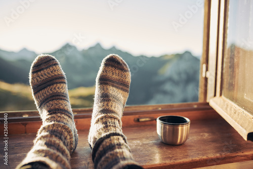Füße mit Wollsocken auf einer Fensterbank und Blick auf die Berge