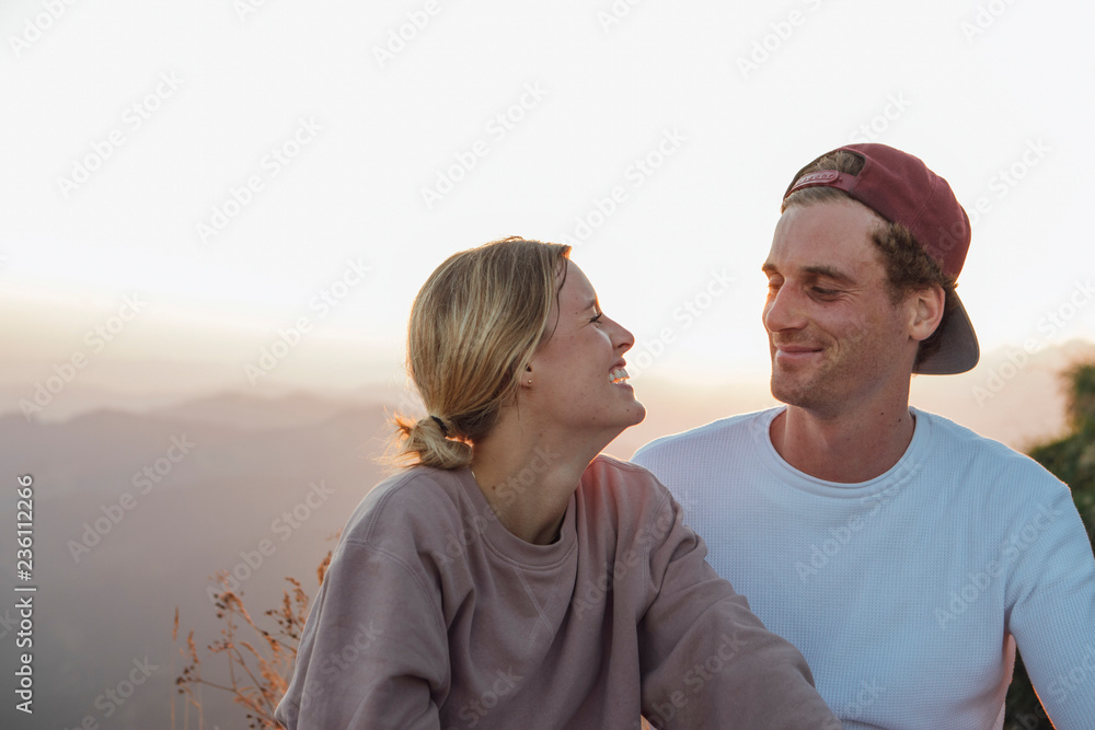 Happy young couple on a hiking trip having a break at sunrise Happy young couple on a hiking trip having a break at sunrise