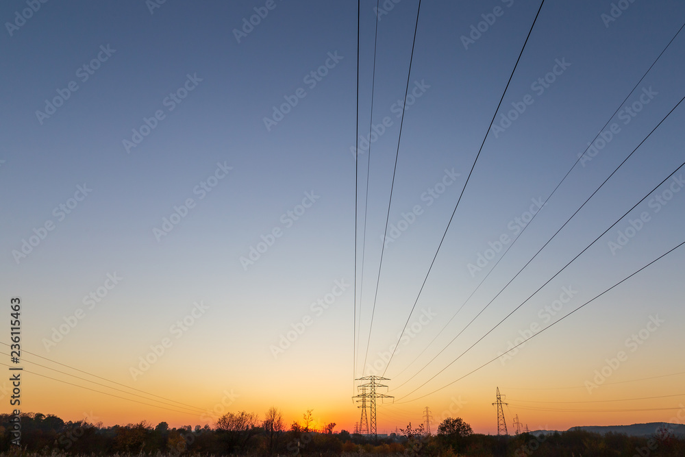 Landscape with the setting sun and power poles