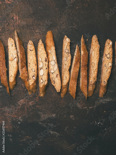 Biscotti - Traditional Italian Almond Dessert On Dark Copper Background. Cookies Arranged On The Top Of Third Of The FrameWith Copy Space. Top View, Selective Focus, Vertical Composition. photo