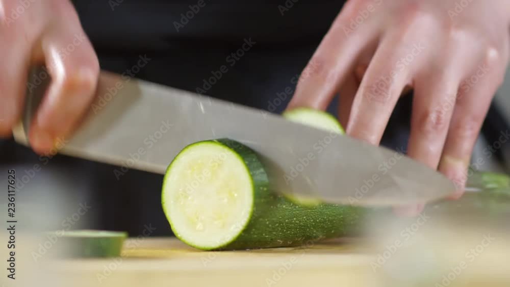 Close up shot of hands of unrecognizable male cook cutting zucchini with sharp knife Close up shot of hands of unrecognizable male cook cutting zucchini with sharp knife