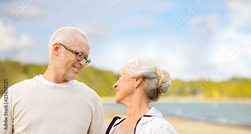 old age, retirement and people concept - happy senior couple talking over beach background