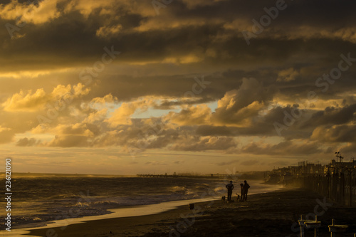People playing with dog on the beach at sunset © tasha