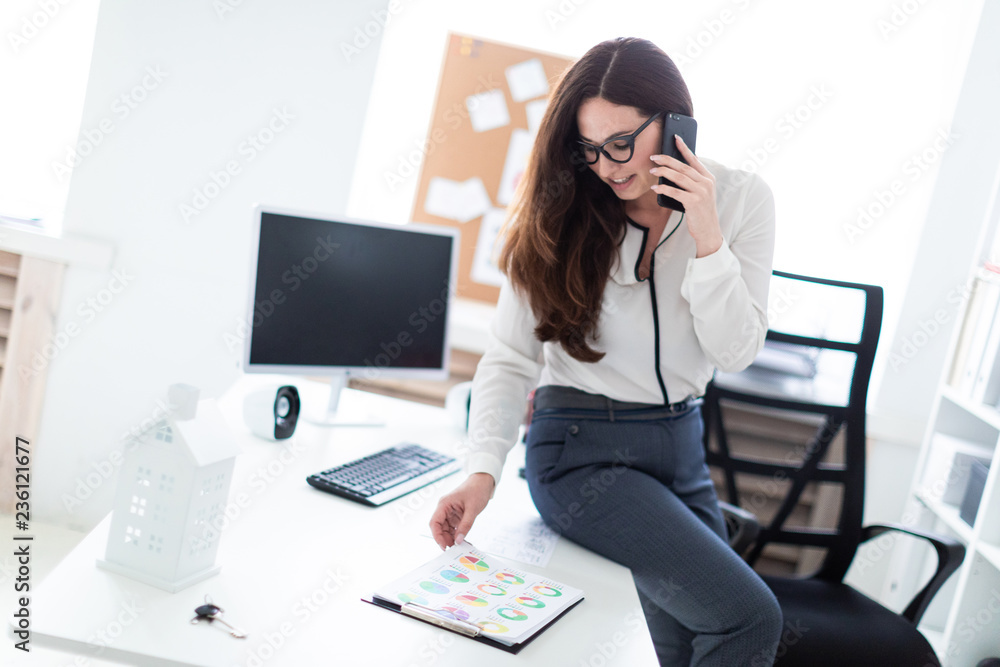 The young girl sat down on the table, talking on the phone and watching the graphics. The young girl sat down on the table, talking on the phone and watching the graphics.