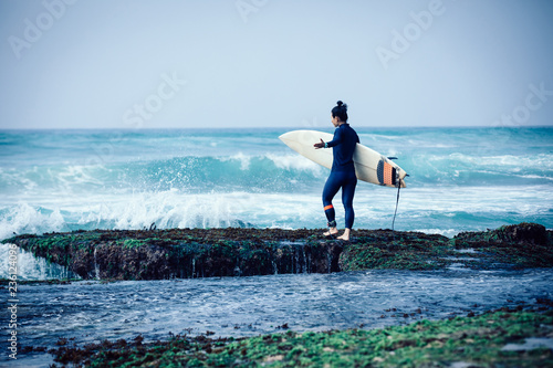 Woman surfer with surfboard going to surf the big waves