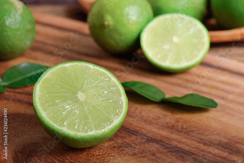 whole and half cut fresh lime with leaf on wooden background