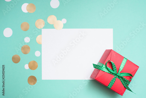 Decorated gift box, confetti and blank white sheet of paper.