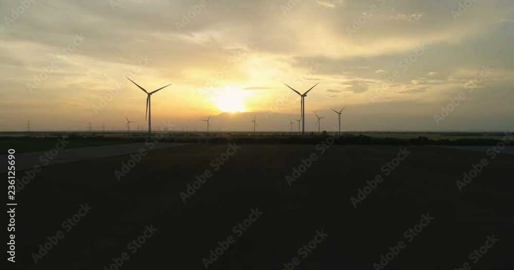 Aerial shot over beautiful landscape with wind turbines in view at sunset Aerial shot over beautiful landscape with wind turbines in view at sunset