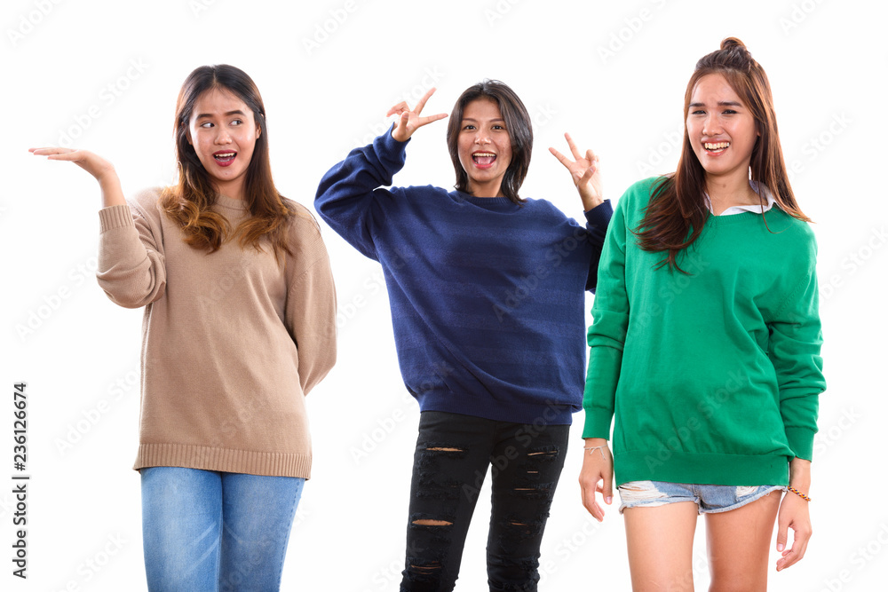 Studio shot of three happy young Asian woman friends smiling and Studio shot of three happy young Asian woman friends smiling and