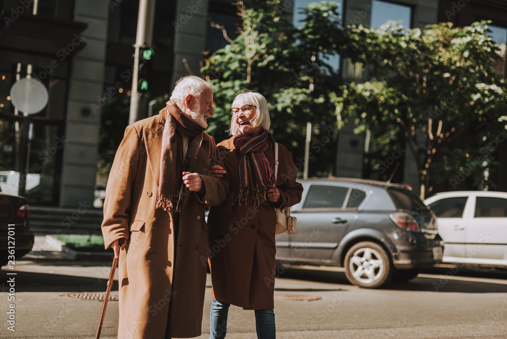 Portrait of stylish bearded gentleman with cane spending time with his wife outdoors. They looking at each other and smiling Portrait of stylish bearded gentleman with cane spending time with his wife outdoors. They looking at each other and smiling