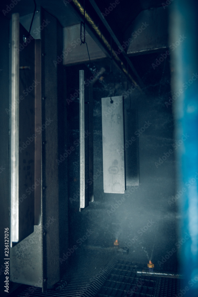 Fototapeta premium Industrial sheet metal steel products on a production line in an industrial factory setting, with atmospheric lighting. Being prepared for paint treatment. Industrial sheet metal.