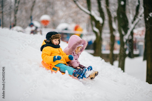 Happy children move down hill on Board. Funny children's winter games