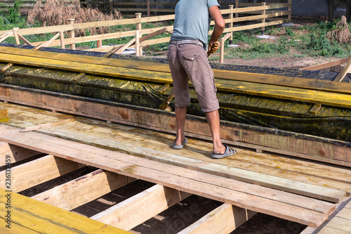 Worker at a construction site at home covers antiseptic boards. Impregnation of boards.