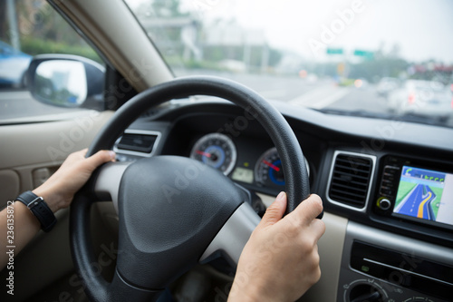 Hands holding steering wheel while driving car on city road © lzf