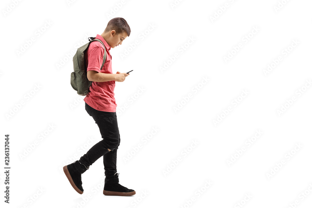 Trendy schoolboy walking and looking at a mobile phone Trendy schoolboy walking and looking at a mobile phone