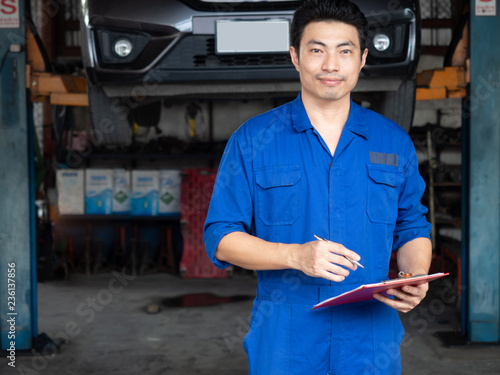 handsome asia man automotive mechanc in garage with copy space