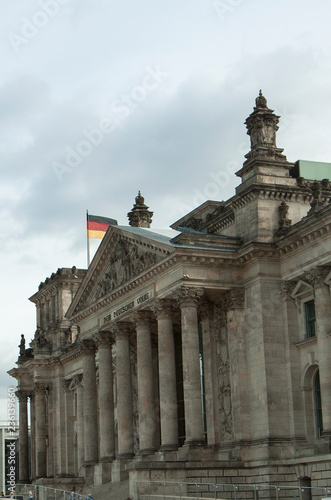 The majestic old building of the Reichstag Parliament in Berlin. Gray building on a cloudy sky background. German flags.City landscape.