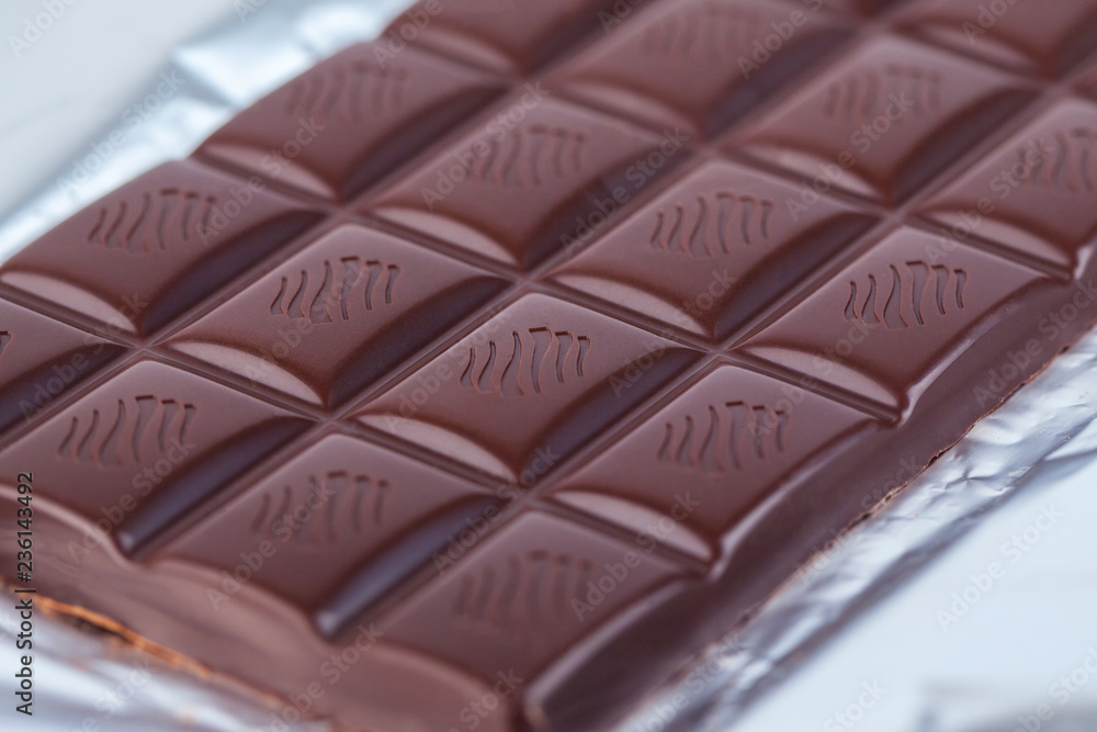 Fototapeta premium Dark chocolate bar in opened silver foil. Sweet food