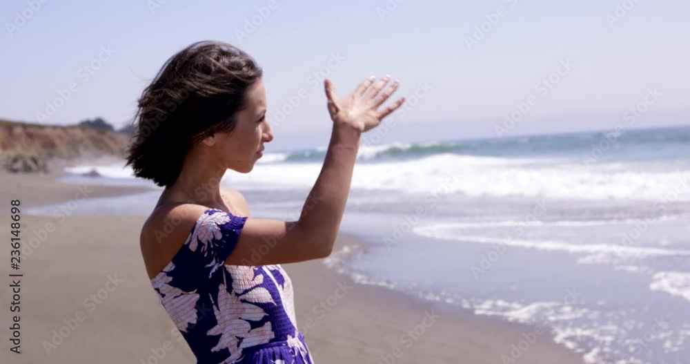 Young woman looking out towards ocean from beach - medium shot Young woman looking out towards ocean from beach - medium shot