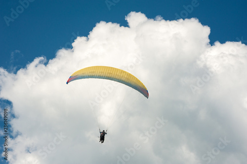 Alone paraglider flying in the blue sky against the background of clouds. Paragliding in the sky on a sunny day.