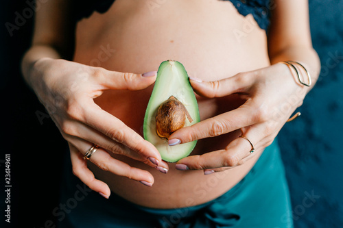 close-up of avocado on background of pregnant belly photo