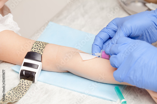 Nurse takes a blood sample from little girls arm - pediatric venipuncture procedure