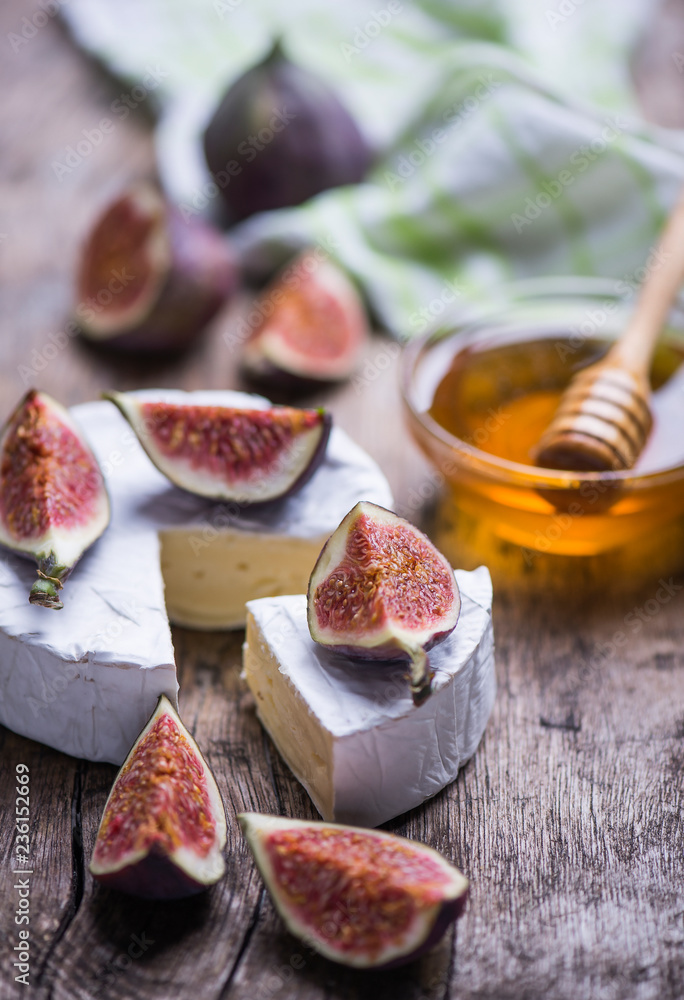 Homemade soft cheese, figs, grape on a wooden background with copy space.