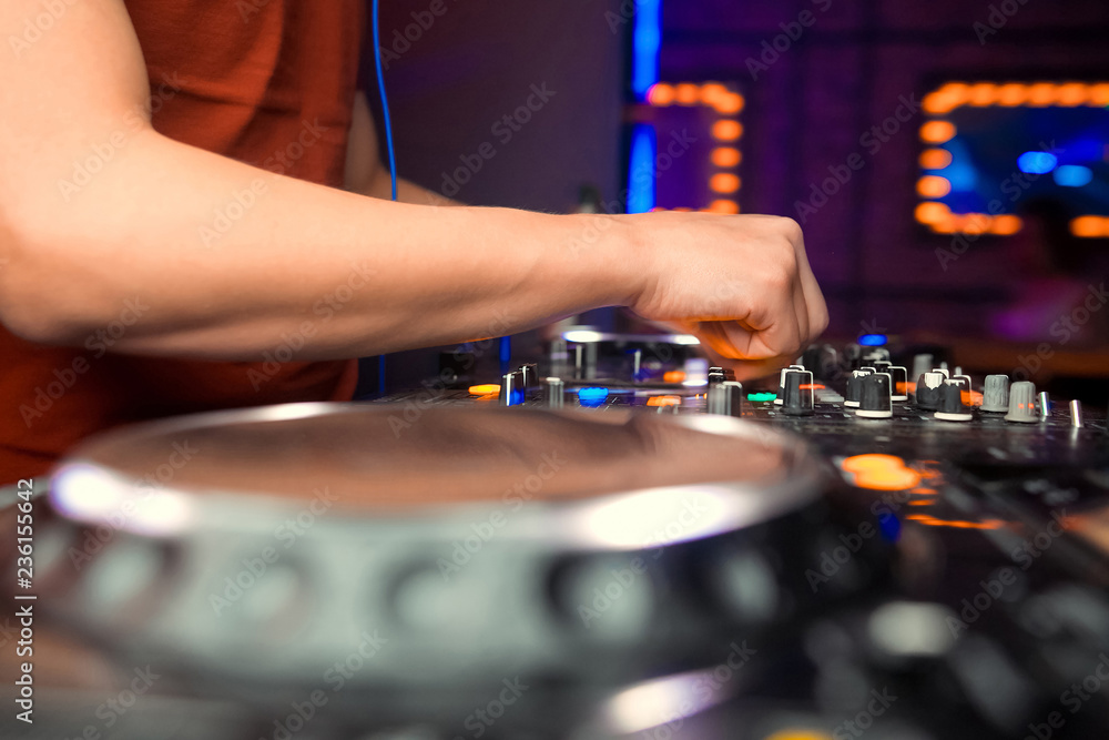 Dj mixes the track in the nightclub at party. In the background laser light show Dj mixes the track in the nightclub at party. In the background laser light show