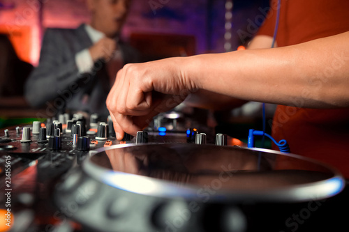 Dj mixes the track in the nightclub at party. In the background laser light show