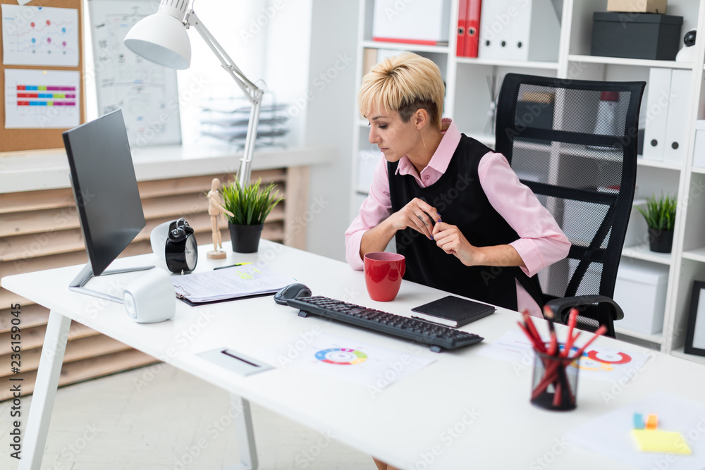 The girl works in the office with a marker and documents. The girl works in the office with a marker and documents.