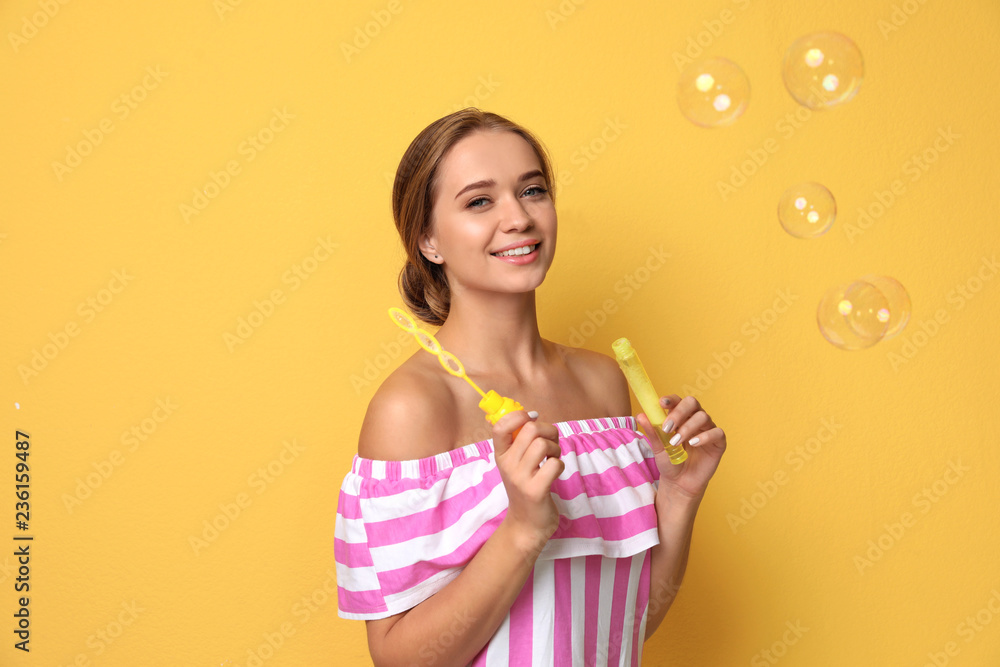 Young woman blowing soap bubbles on color background Young woman blowing soap bubbles on color background