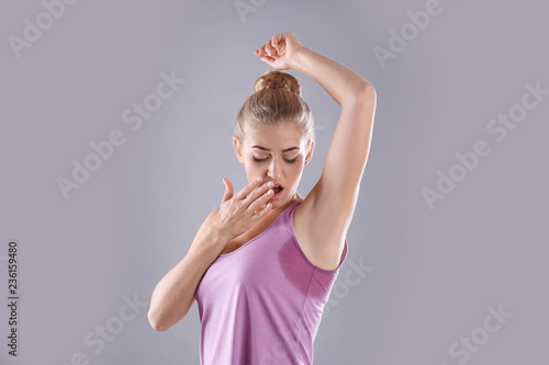 Fototapeta Naklejka Na Ścianę i Meble -  Young woman with sweat stain on her clothes against grey background. Using deodorant