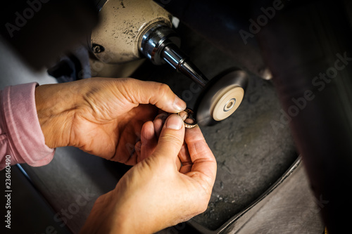 Jeweler polishes gold ring on bench grinder in jewellers workshop
