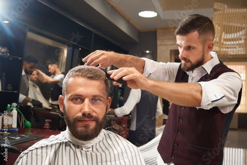 Man sitting in chair in barber shop during process of haircut