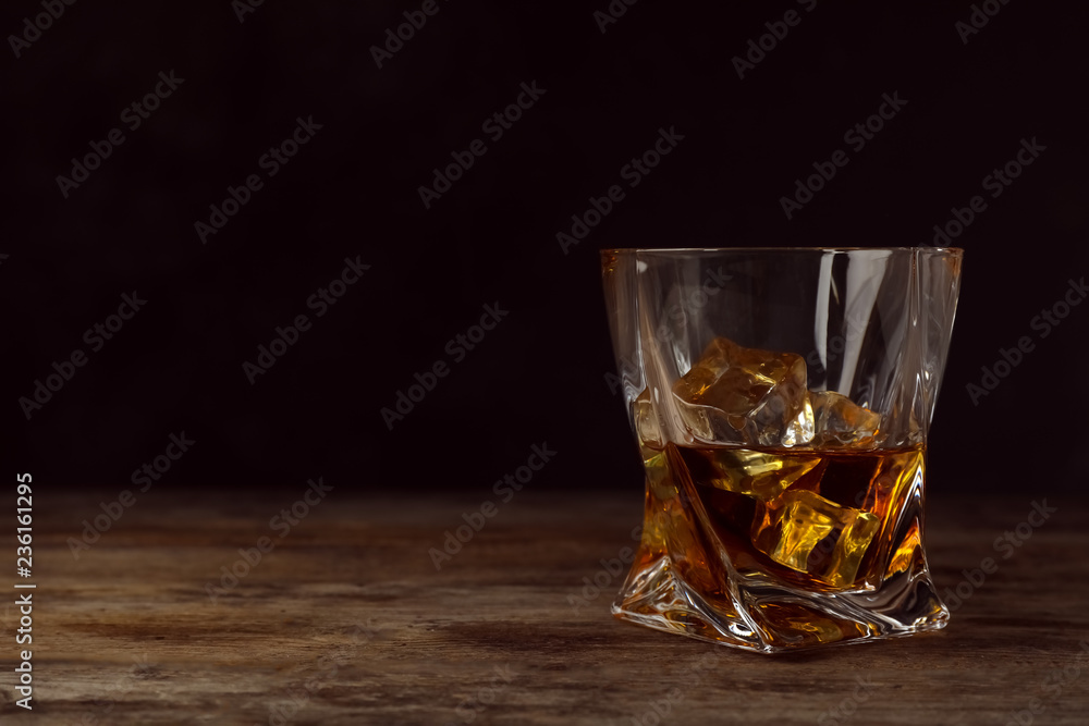 Golden whiskey in glass with ice cubes on table. Space for text Golden whiskey in glass with ice cubes on table. Space for text